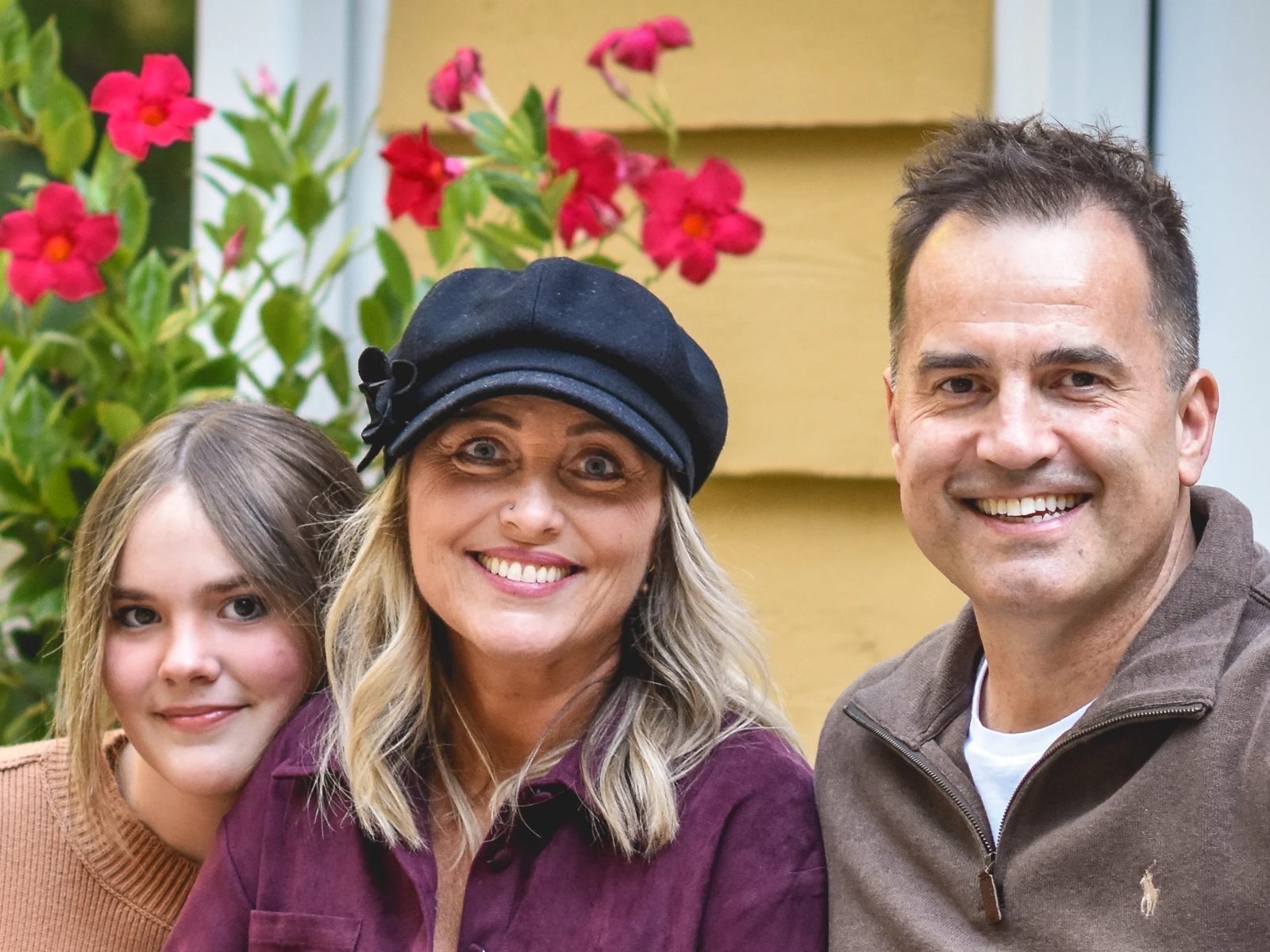 Athena, Joanne and Chris together in front of the house, smiling